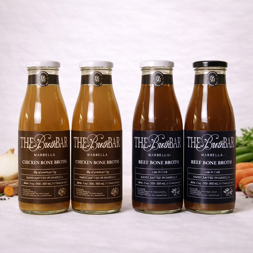 Four bottles of The Broth Bar bone broth on a white background with vegetables.
